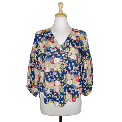 This v neck blouse features a gorgeous coral and white floral print on a blue background, paired with a 3/4 gathered sleeve and flowing body for a fun and pretty look. Perfect for any occasion!