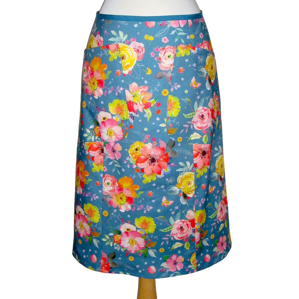 Midi Cotton skirt in a vintage floral print with large patch pockets. Flowers are yellow red and pink over a teal background.